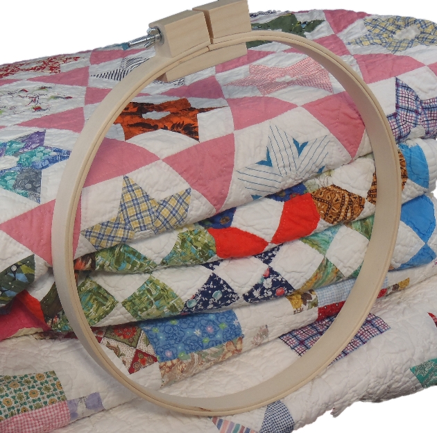 Wooden needlework frame next to handcrafted quilts