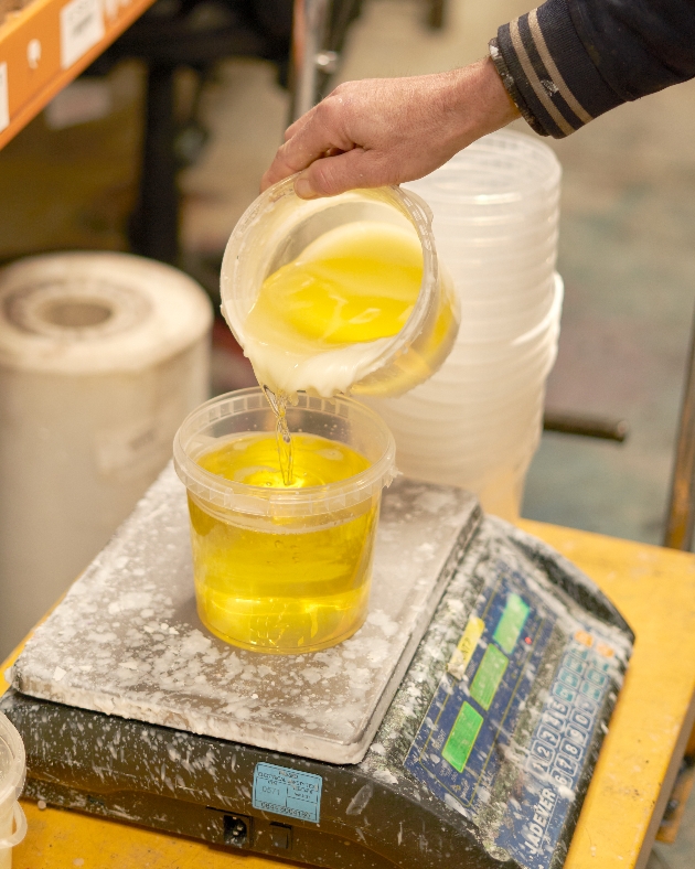 factory showing man pouring candle wax into vessel