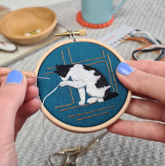 Embroidery hoop with a black and white cat design