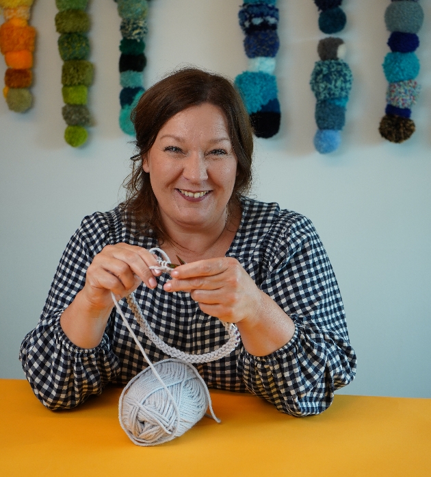 Merion Willis, in spotty top at a table knitting