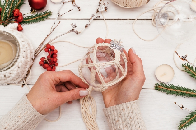 hand doing macrame around a glass ball