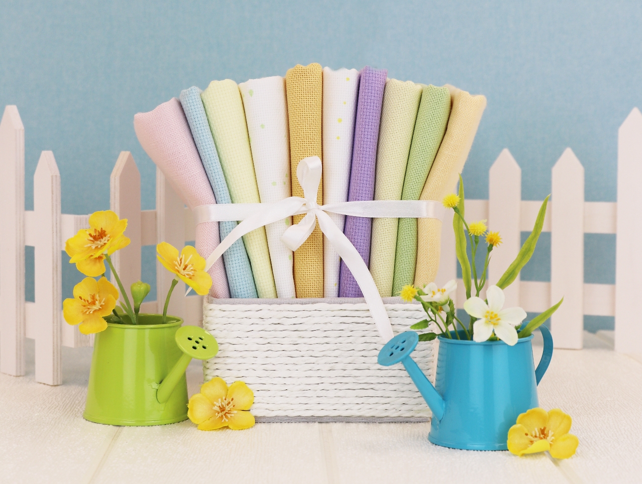 pastel fabric in a white basket with a bow