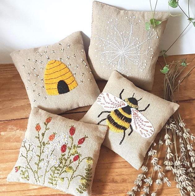 four hessian pillows with bee images stitched on