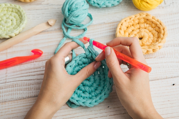 woman's hands doing crochet with turquoise wool