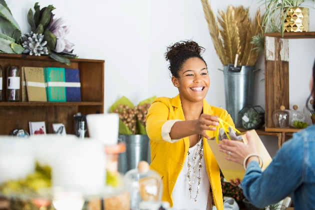 lady wearing yellow jacket behind a counter at a gift shop serving customer