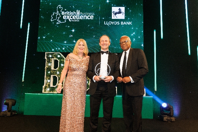 Curious Universe team holding award with Sir Trevor McDonald at awards ceremony