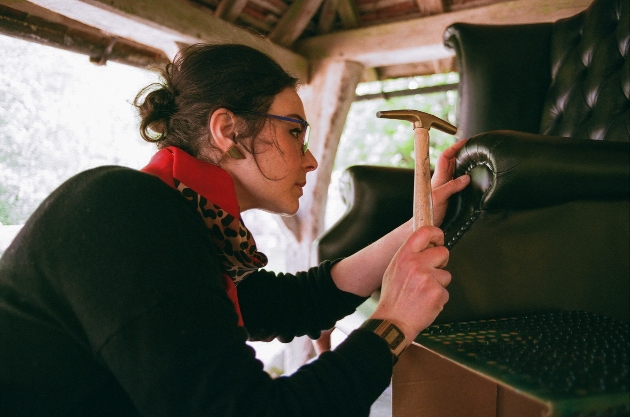 Lady doing upholsterery work on an armchair