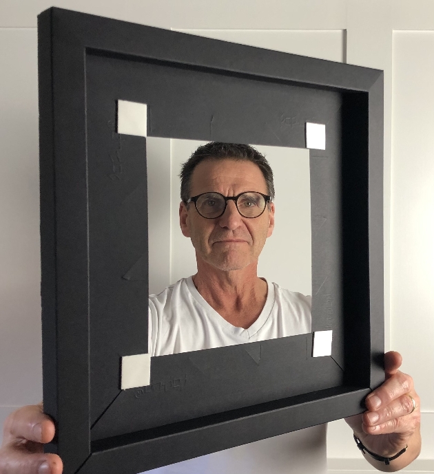 male head looking through black paper photo frame