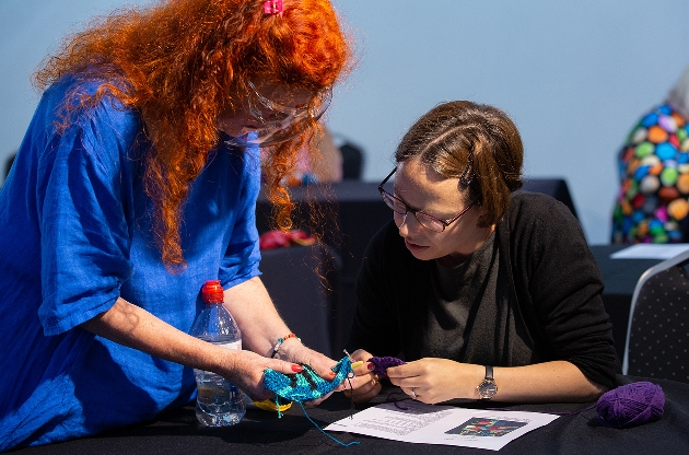 lady helping a woman crochet in a knitting workshop