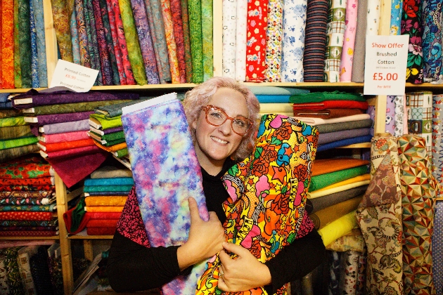 lady smiling holding rolls of fabrics