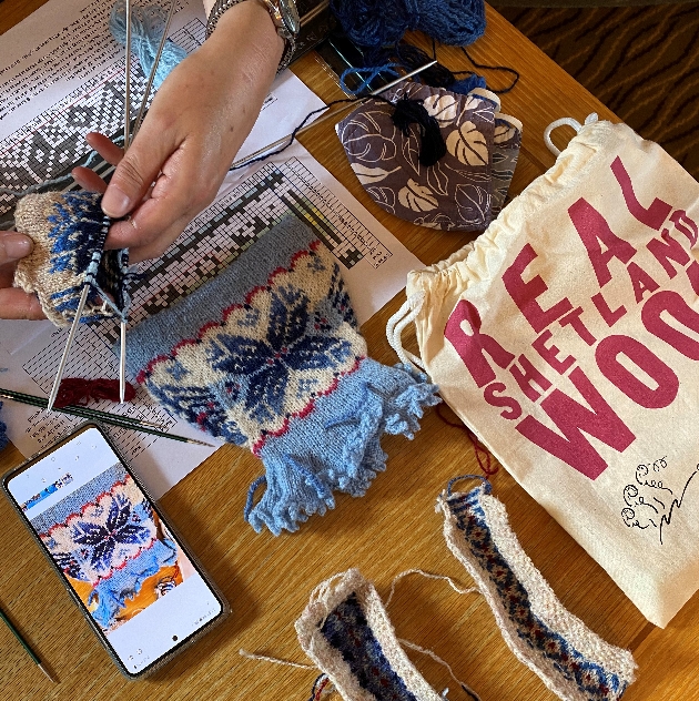 woman's hands knitting with blue wool