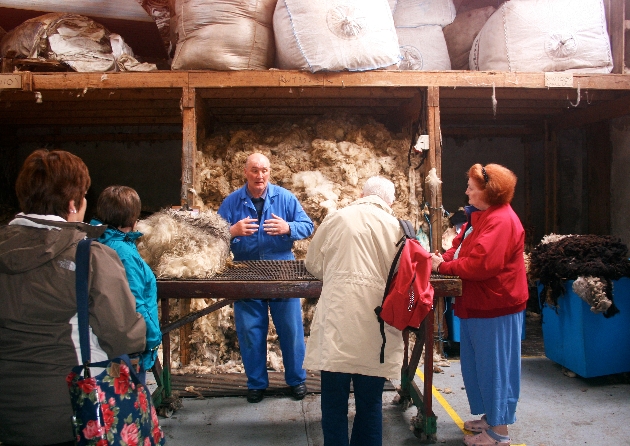 man in blue overalls presenting to group about a wool factory