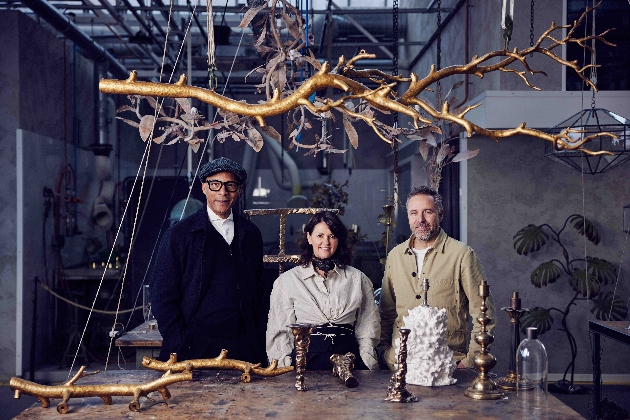 three people standing at a table adorned with sculptures