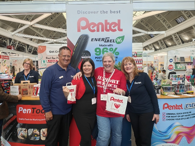 GROUP SHOT OF PENTEL STAFF IN FRONT OF PENTEL BANNER AT EXHIBITION