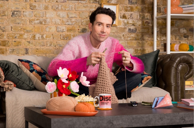 young man crocheting on the couch