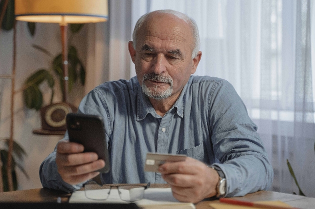 Older man using phone to buy an item with credit card 