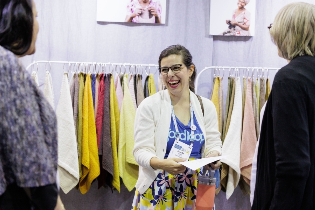 woman smiling in front of rack of fabrics
