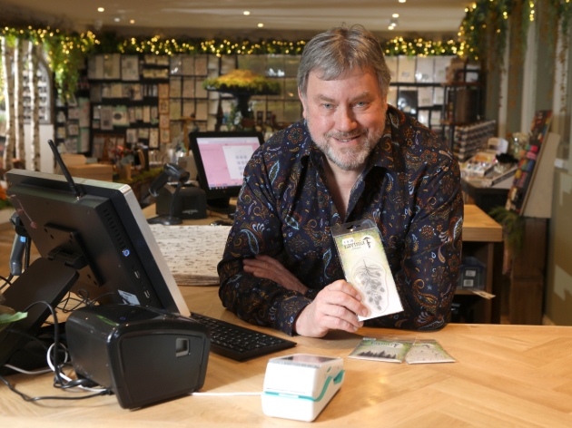 man holding craft product at till point in craft shop