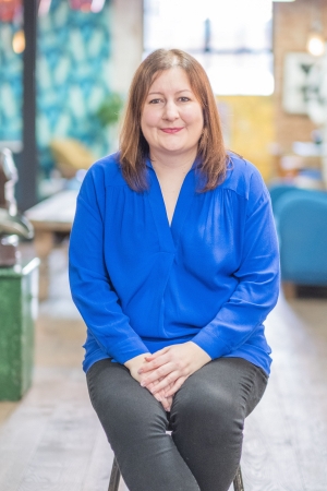 lady in blue shirt with brown bob sitting on a chair