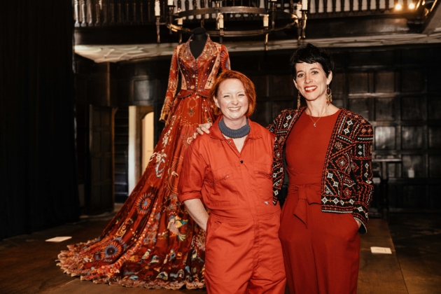 two ladies standing in front of mannequin wearing embroidered red dress