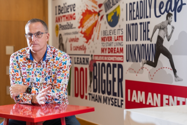 man in colourful shirt sat at a red table